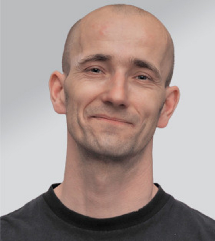 Portrait eines Mannes, der in die Kamera lächelt.